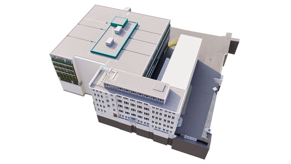 Ein modernes Gebäude von oben, rechteckige Form, Flachdach, große Fensterfronten, mit angrenzendem Parkplatzbereich.