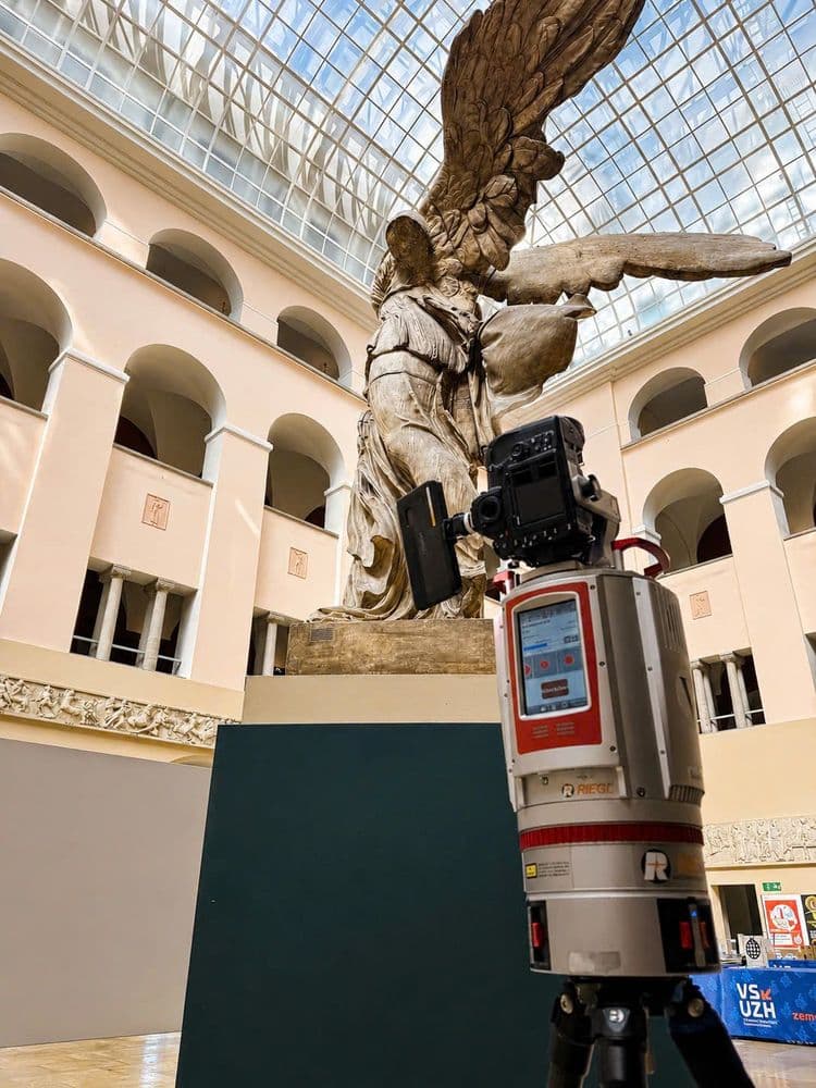 Laserscanner auf Stativ erfasst eine große geflügelte Marmorskulptur in einem Museumshof mit Glasdach und Arkaden – 3D-Vermessung und digitale Dokumentation von Kunstwerken.