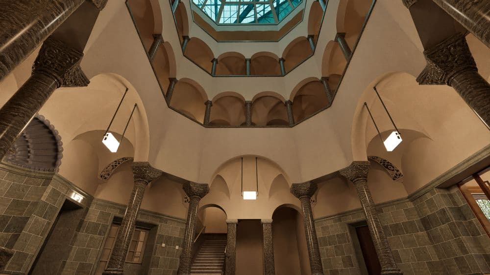 Gebäudeinnenraum mit gewölbter Decke, verziert mit Säulen und Rundbögen.