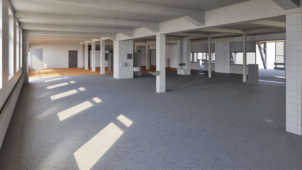 Ein leerer, sonnendurchfluteter Industriebereich mit sichtbaren Betonpfeilern und großen Fenstern.