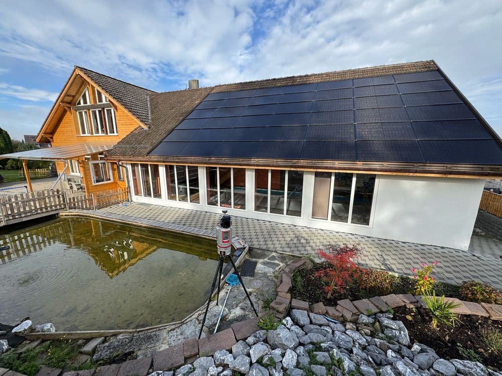 Gemütliches Holzhaus mit Solardach neben einem Teich und Garten.