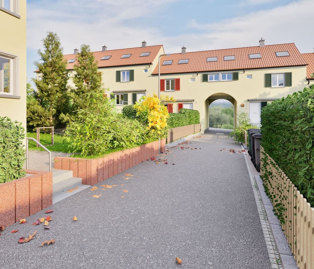 Reihenhäuser mit roten Dächern in einer ruhigen Wohnstraße, umgeben von Grünanlagen und herbstlichem Laub.