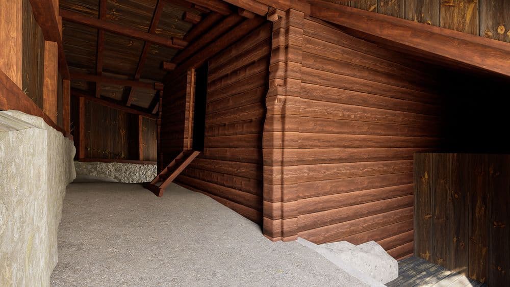 Überdachter Holzschuppen aus braunen Holzbrettern mit Betonboden und Stützbalken, perspektivischer Blick in den Gang, rustikale Scheunen- oder Lagerhaus-Architektur.