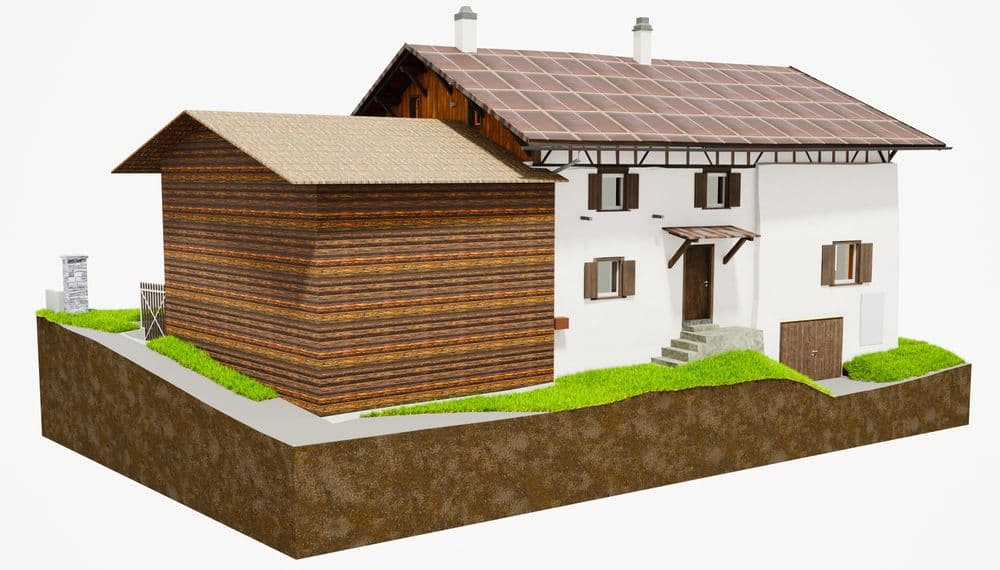 Ein traditionelles Holzhaus mit weißen Fassaden, Holzdach und Nebenbau, umgeben von Rasen auf einer erhöhten Plattform.
