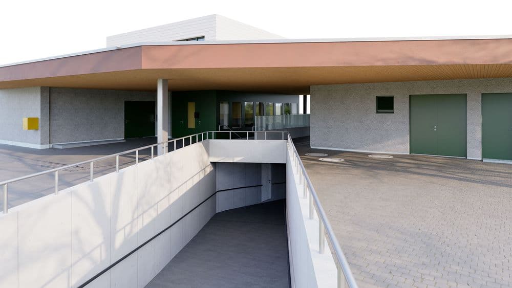 Modernes Gebäude mit überdachtem Eingangsbereich und angrenzender Zufahrtsrampe.