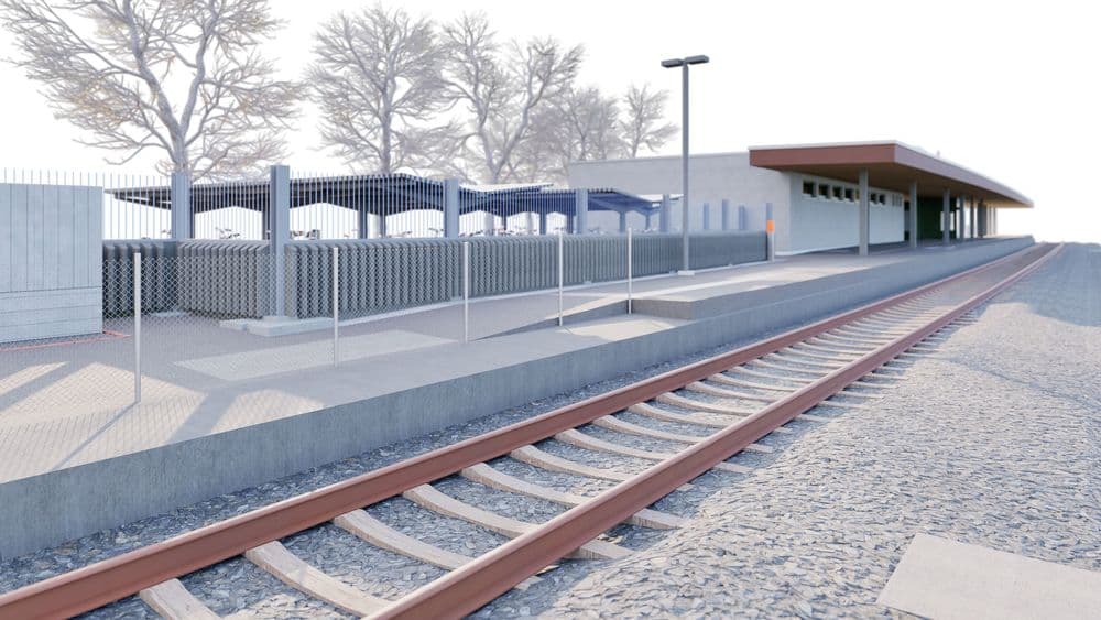 Ein moderner, leerer Bahnsteig mit Gleisen und überdachten Wartebereichen.
