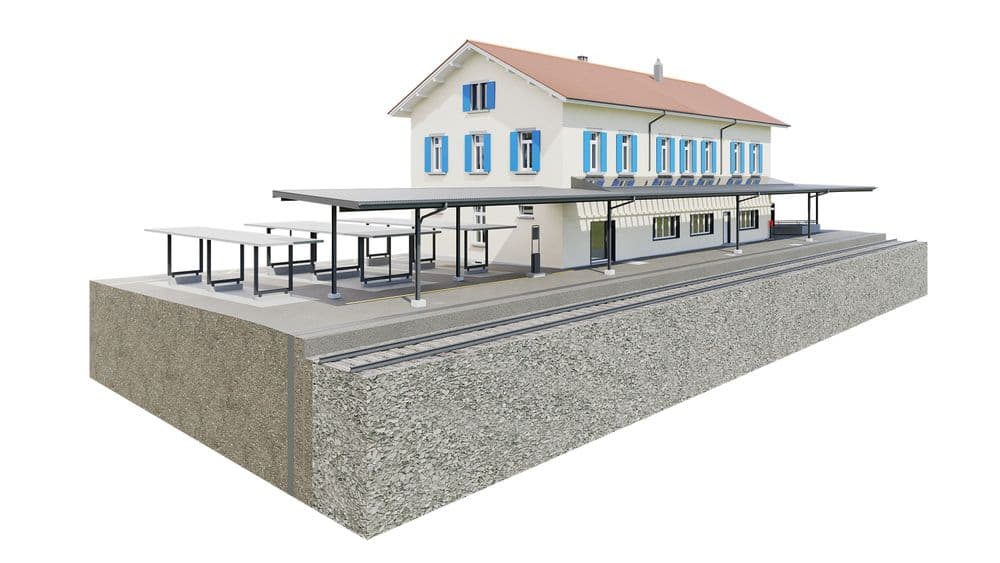 Ein detailliertes Modell eines Bahnhofs mit zweistöckigem Gebäude, Bahnsteig und Schienen.