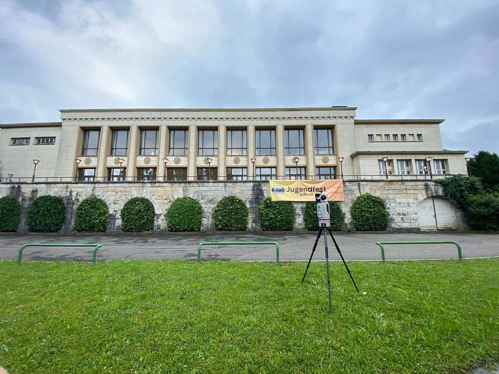 Es ist ein großes historisches Gebäude mit einem Plakat, auf dem "Jugendfest" steht, umgeben von Rasen und Hecken.