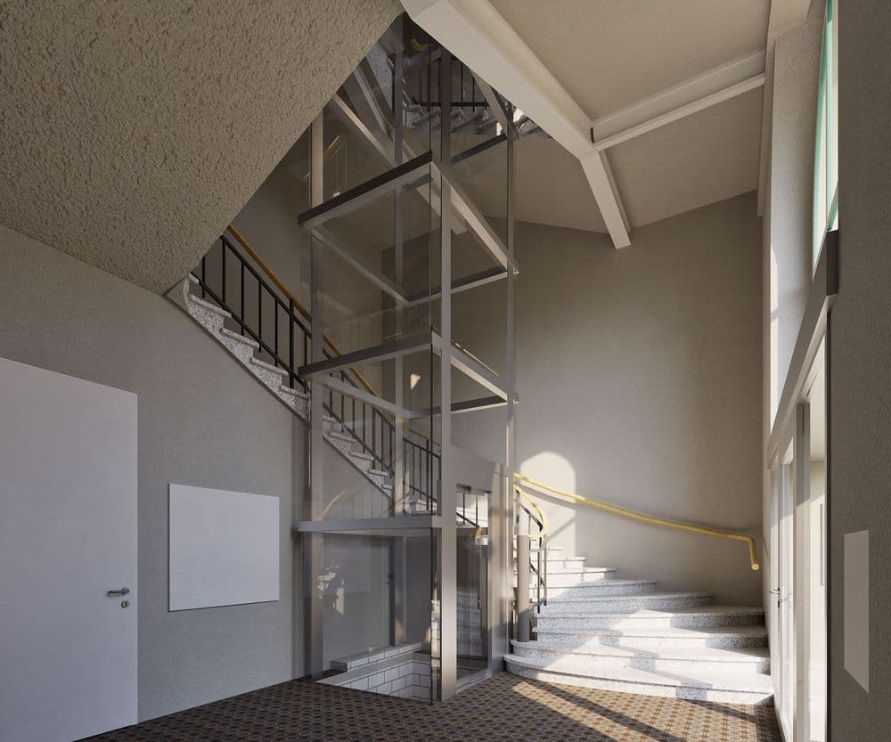 Helles Treppenhaus mit gläsernem Aufzugschacht, weißen Wänden und geschwungener Steintreppe; Sonnenlicht fällt durch große Fenster und wirft Schatten auf den Boden.