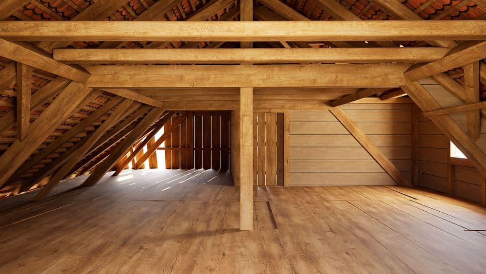 Holzdachboden mit sichtbaren Dachbalken und Holzfußboden, leerer Dachraum mit Licht, Tür und Wandverkleidung, rustikale Dachkonstruktion im Dachgeschoss.