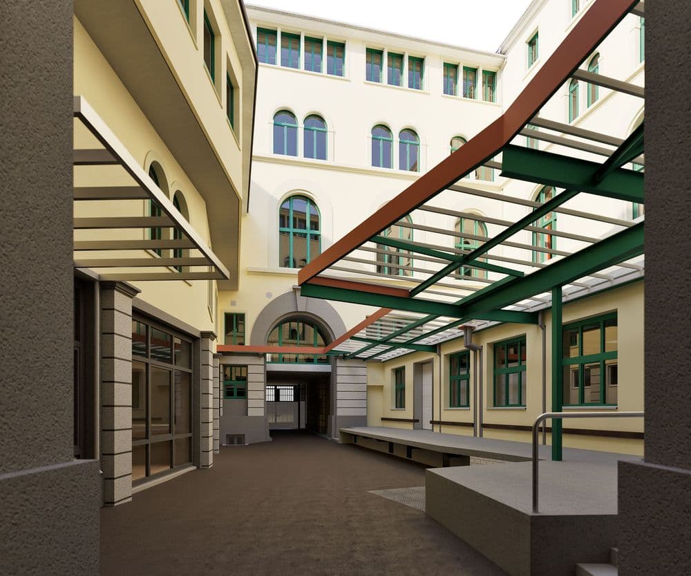 Innenhof eines modernen Büro- oder Schulgebäudes mit überdachtem Glasdach, Arkaden, Fenstern und Eingangsbereich; helle Fassaden und gepflasterter Weg in urbaner Architektur.