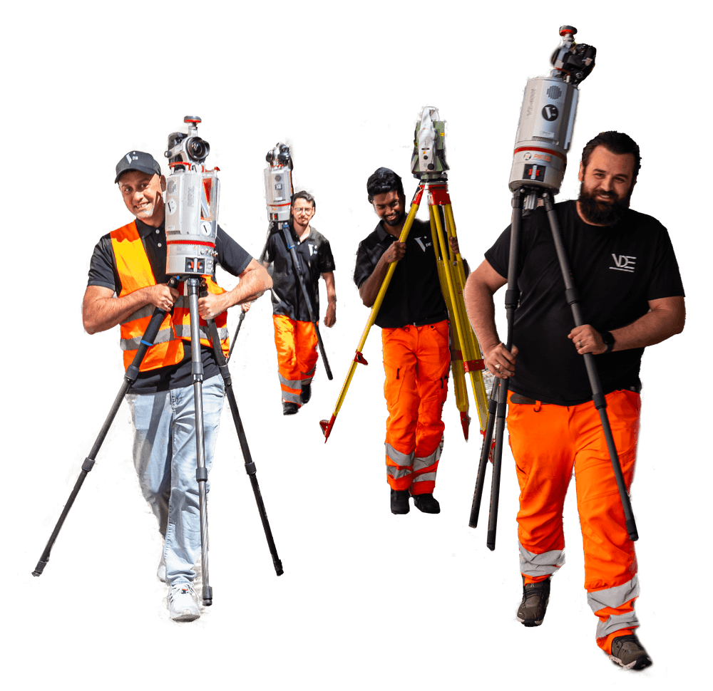 Eine Gruppe von vier Bauingenieuren trägt Vermessungsgeräte. Sie tragen Schutzkleidung und wirken konzentriert.