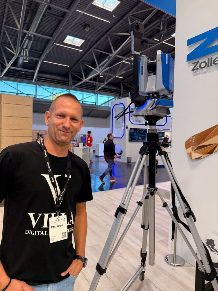 Mann auf einer Messe neben einem 3D-Laserscanner auf Stativ am Zoller‑Stand in einer Ausstellungshalle, im Hintergrund Besucher und Messestände.