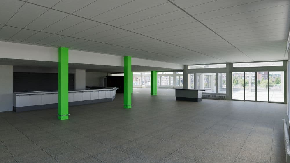 Großer leerer Innenraum mit grauem Fliesenboden, weißen Deckenpaneelen, grünen Stützpfeilern, Thekenbereich links und großen Fensterfronten mit Schiebetüren, Tageslicht und Blick nach draußen.